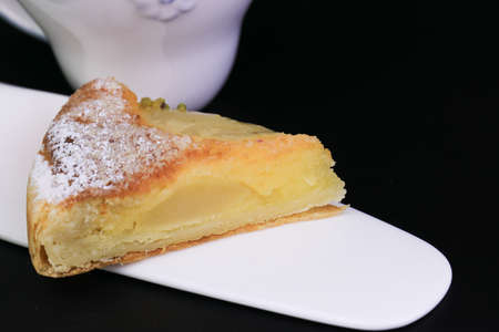 Close up Pear Tart topped with Crushed Pistachio nuts on Black Background