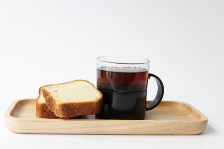 A cup of black tea and bread on a wooden tray on a white background