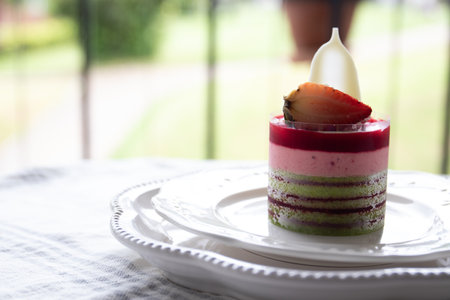 Strawberry mousse cake on white plate with green garden backgroundの写真素材