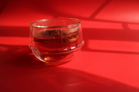 Glass of whiskey on a red background with shadows from the window.の写真素材