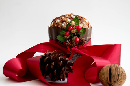 Christmas cake with red ribbon and pine cone on a white background.の写真素材