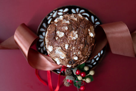 Christmas PANETTONE cake with nuts and red ribbon on a red background
