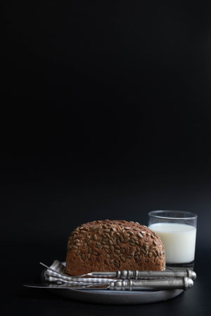 Bread with sesame seeds and a glass of milk on a black backgroundの写真素材