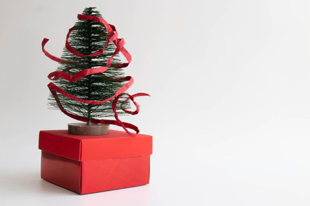 Little Christmas Tree for Decoration placed on red gift box , wrapped with red paper ribbon ,