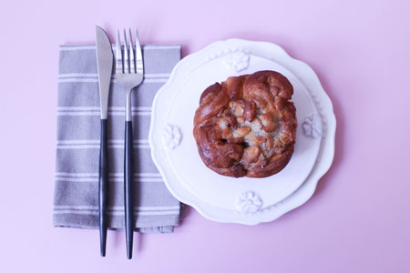 Butter Scotch Bun on a plate with fork and knife on a pink backgroundの写真素材