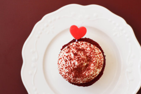 Top View of A Cup Cake topped with Red Heart on Pink Backgroundの写真素材