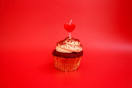 A Cup Cake topped with Red Heart on Red Backgroundの写真素材