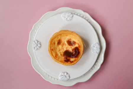 Pastel de nata, Custart Tart on a white plate on a pink background, top view