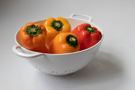 Colorful bell peppers in a white bowl on a white background.の写真素材