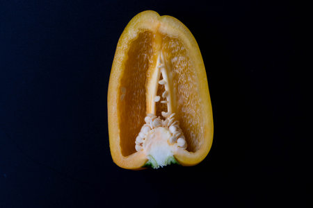 Sliced yellow bell pepper on a black background. Close up.