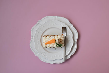 Carrot cake in white plate with fork and knife on pink backgroundの写真素材