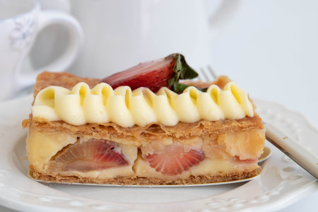 French Pastry , MilleFuille topped with Strawberry  on white dish with coffee cup on background.の写真素材