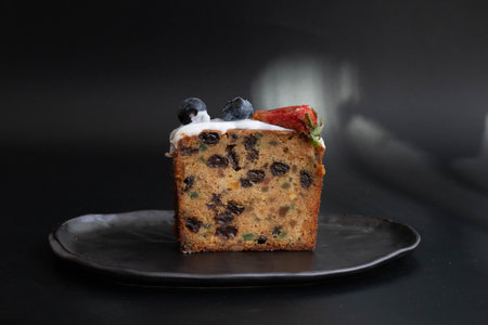 Homemade cake with raisins and blueberries on black backgroundの写真素材