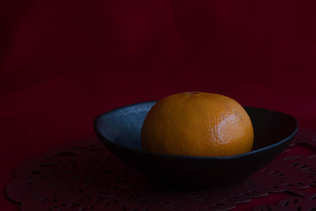 Oranges in a black bowl on a red background. Selective focus.の写真素材