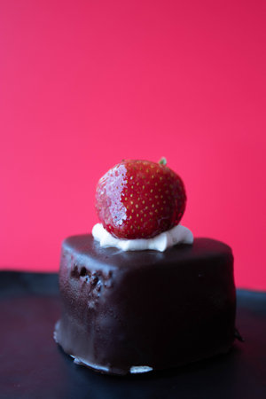 Chocolate cake topped with Fresh Strawberry on Red backgroundの写真素材