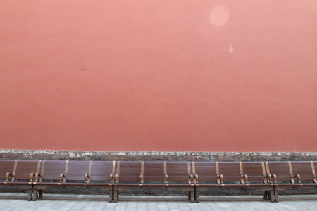 Empty bench and red wall in the city. Perspective view of empty bench.の写真素材