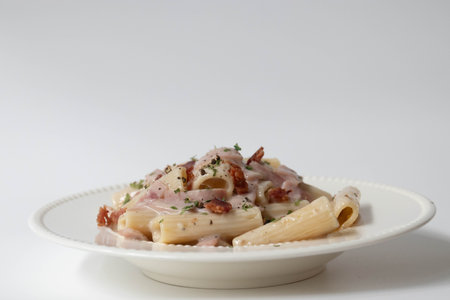 Penne alla carbonara with bacon and cheese on a white background