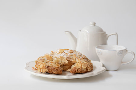 Almond cake with cup of coffee and teapot on white backgroundの写真素材