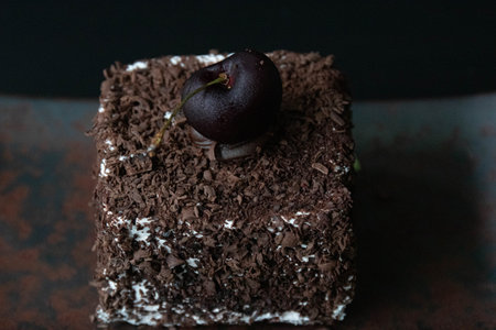 Chocolate cake with cherries on top on a dark background.