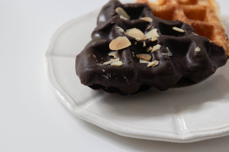 Belgian waffles with chocolate and almonds on a white plate.