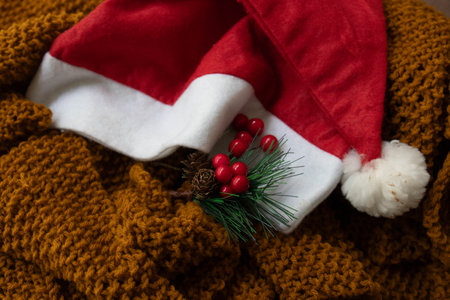 Red Santa Hat with a bouquet of Red Berries on Brown Knit Woolの写真素材