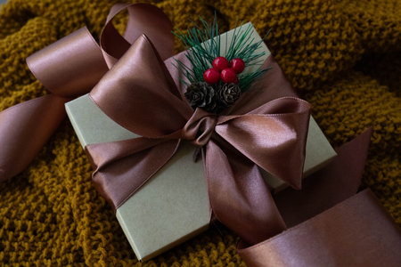 A cardboard Gift Box with Copper Satin Ribbon and a bouquet of Red Berries on rustic backgroundの写真素材
