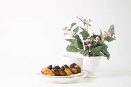 Cup of coffee with eclairs and flowers on white background