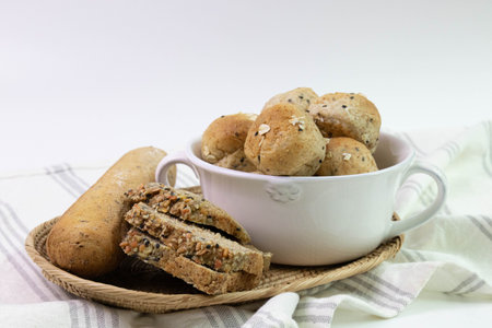 Organic Bread, Healthy Food Concept , Golden-brown rolls, flecked with dark seeds and oat flakes in a white bowl, white backgroundの写真素材