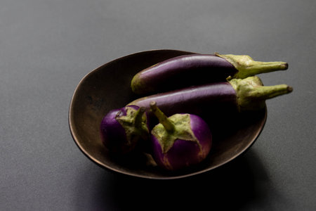 Deep purple, round and oblong eggplants on Black backgroundの写真素材
