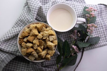 A simple and minimalistic breakfast setup featuring a bowl filled with golden-brown bread croutons alongside a cup of milk tea or coffee with milk.の写真素材