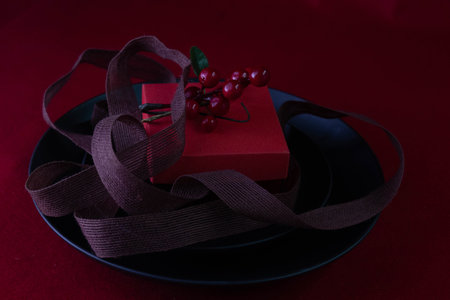 Red Gift Box decorated with red berries on black plate , red backgroundの写真素材