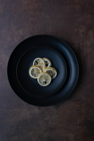 A close-up image of translucent dried lemon slices layered against a dark background. The texture and fragility of the slices highlight the natural beauty of preserved citrus.の写真素材