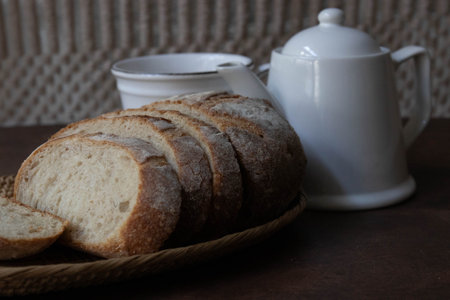 Sliced white bread on wooden table with teapot.の写真素材