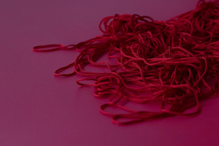 red threads on a pink background, close-up, copy spaceの写真素材