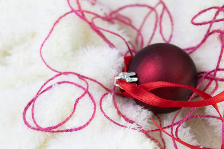 christmas ball with red ribbon on white fur background, closeup