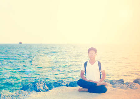 The  man sitting in meditation  on the rock  soft  focusの写真素材
