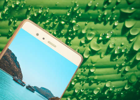mobile  with  island  picture  on green leaf with dew drop  texture  abstract  technology and ...