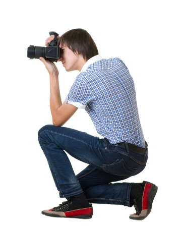 Young man photographer doing photos by digital camera isolated on white backgroundの写真素材