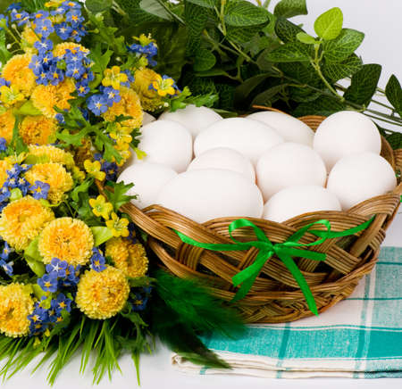 Basket with Easter eggs and springflowers on white backgroundの写真素材