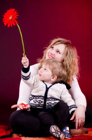 Portrait of mother and young baby boy with red flowerの写真素材