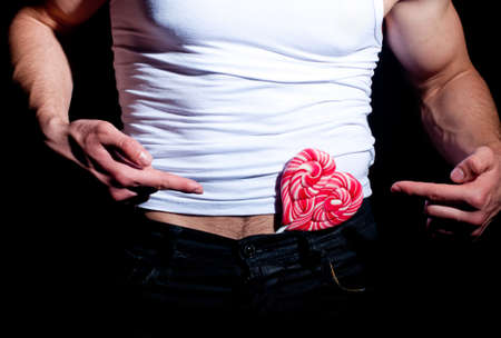 Fashionable muscular man with red lollipopの写真素材