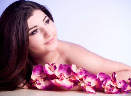 Beauty face of the young woman with flower on color backgroundの写真素材