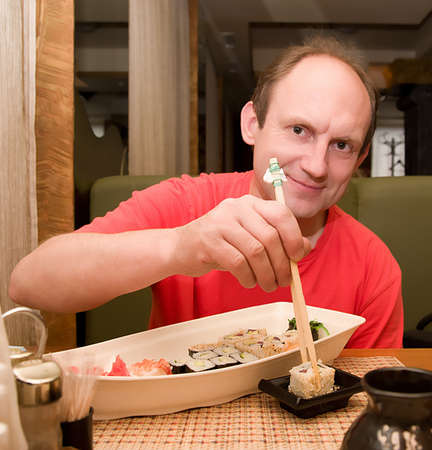 Happy aged man with set of sushi rolls on the white plateの写真素材