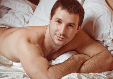 Young sexy muscular man in a bedの写真素材
