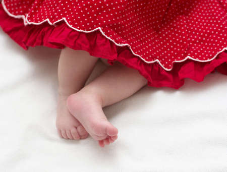 Newborn baby girl feet in red dress