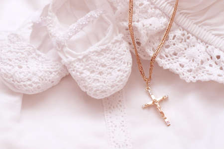 Baby shoes and white dress with golden cross for Christeningの写真素材