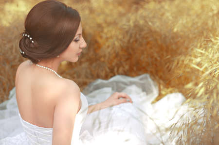 Beautiful bride with stylish make-up in white dress in spring gardenの写真素材