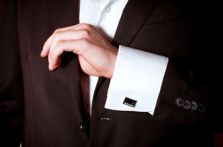 Closeup of a man in black suit correcting a sleeve