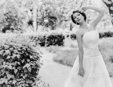 Beautiful bride with stylish make-up in white dress in spring gardenの写真素材