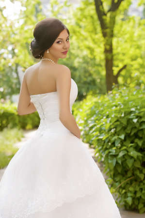 Beautiful bride with stylish make-up in white dress in spring gardenの写真素材